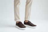 Modisches Bild eines Mannes in braunen Sneakers, der in urbaner Umgebung läuft