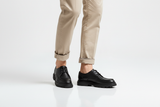 Model trägt schwarze flotte Leder-Schnürboots bei urbanem Spaziergang