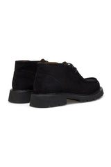 Boots displayed on a wooden floor, highlighting their sleek silhouette.