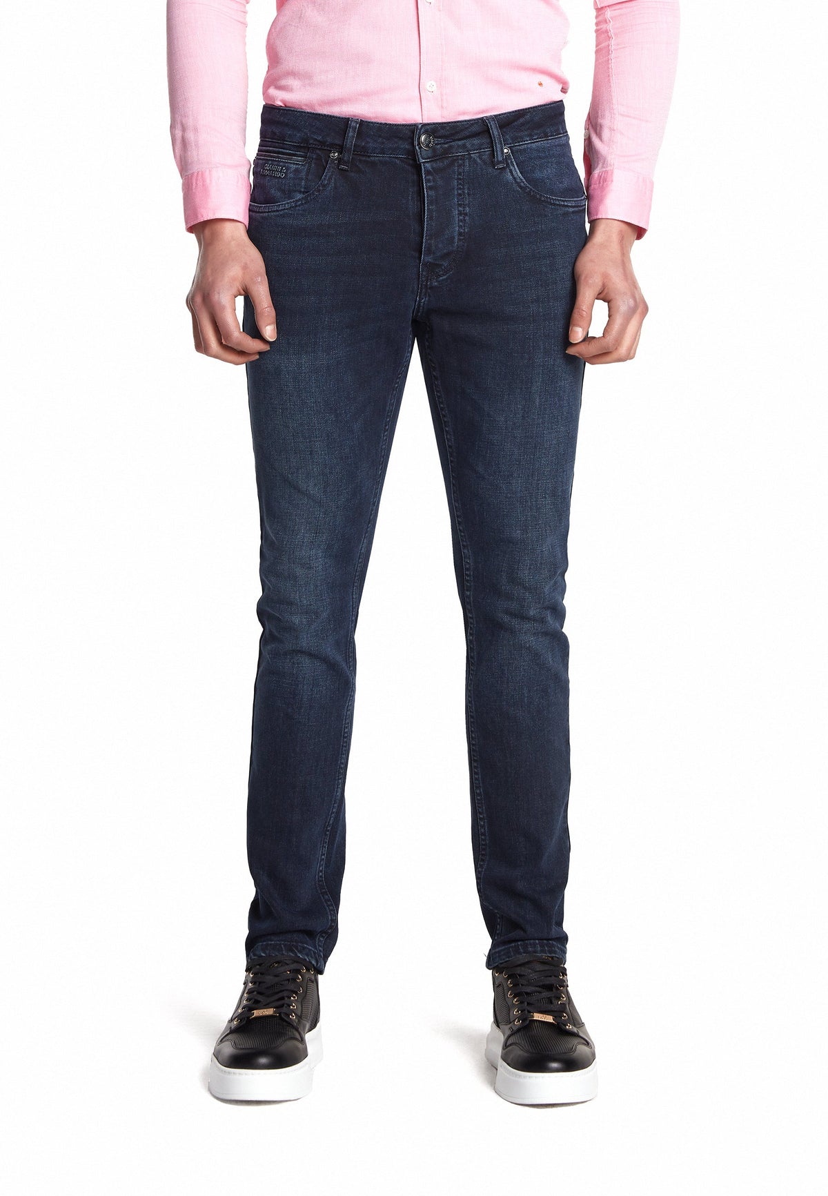 Le modèle porte le jean slim en bleu-noir avec une tenue décontractée
